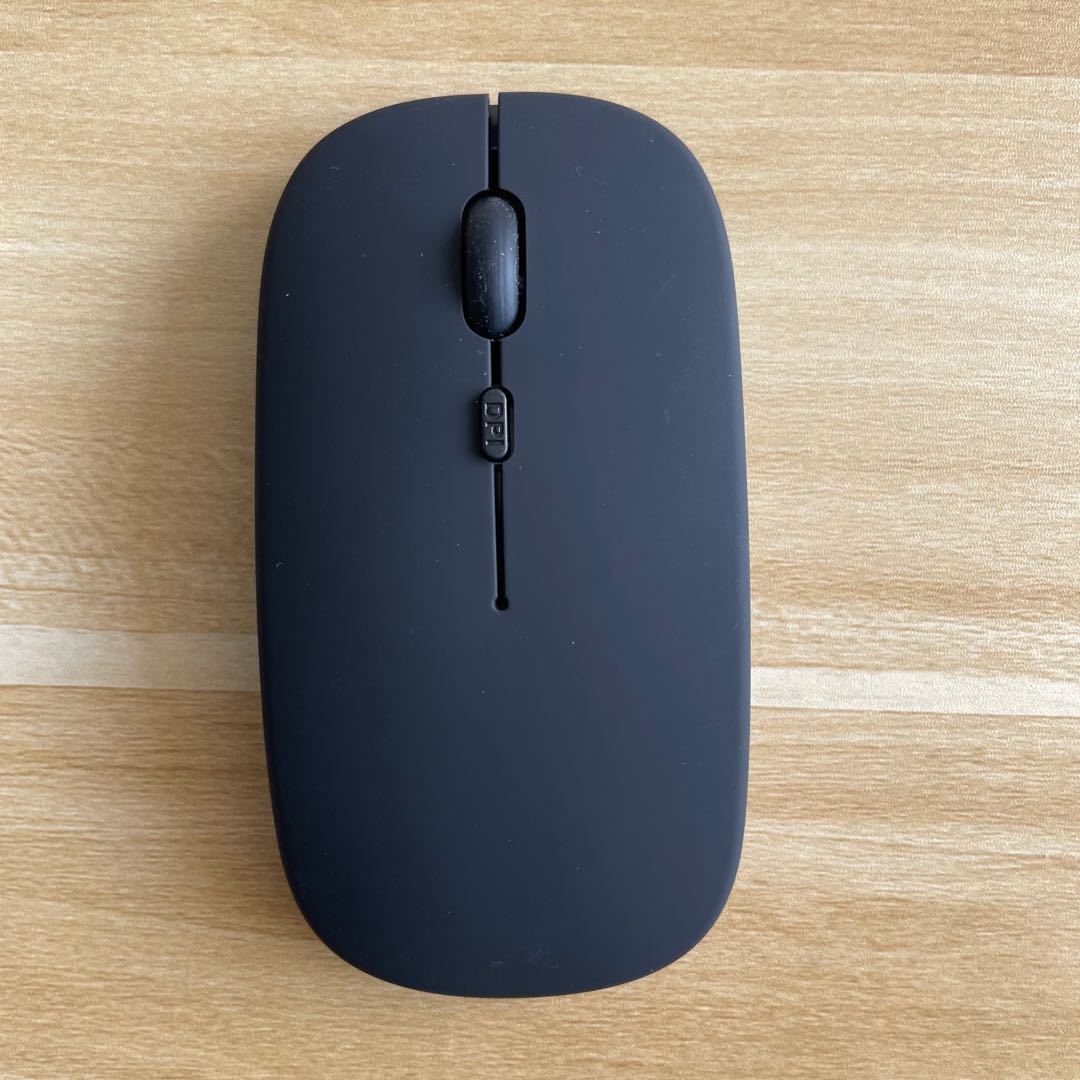 Mouse Dual-mode Charging Wireless Mouse on a wooden surface, showcasing its sleek design and Bluetooth connectivity.